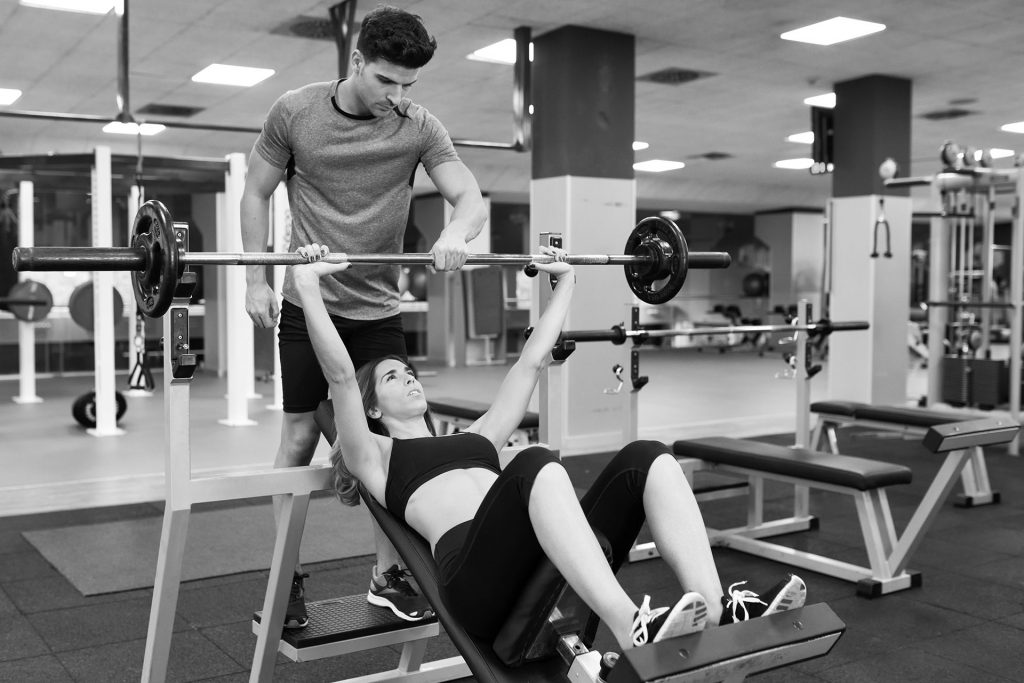 Personal trainer training a young woman at a gym