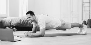 man-exercising-at-laptop-doing-plank-during-online
